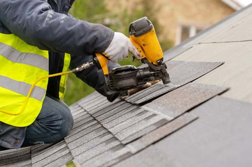 roofer nailing shingles on roof