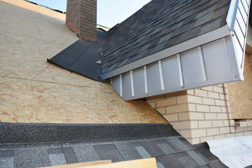 A black square box vent installed on a textured grey shingled roof.