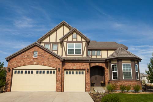 A large brick home at dusk featuring a roof-mounted solar panel array and illuminated windows.