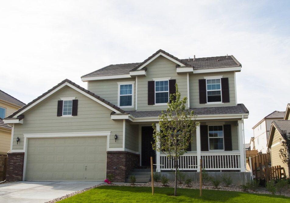 Modern two-story suburban home featuring sage green siding, dark window shutters, and a concrete tile roof.