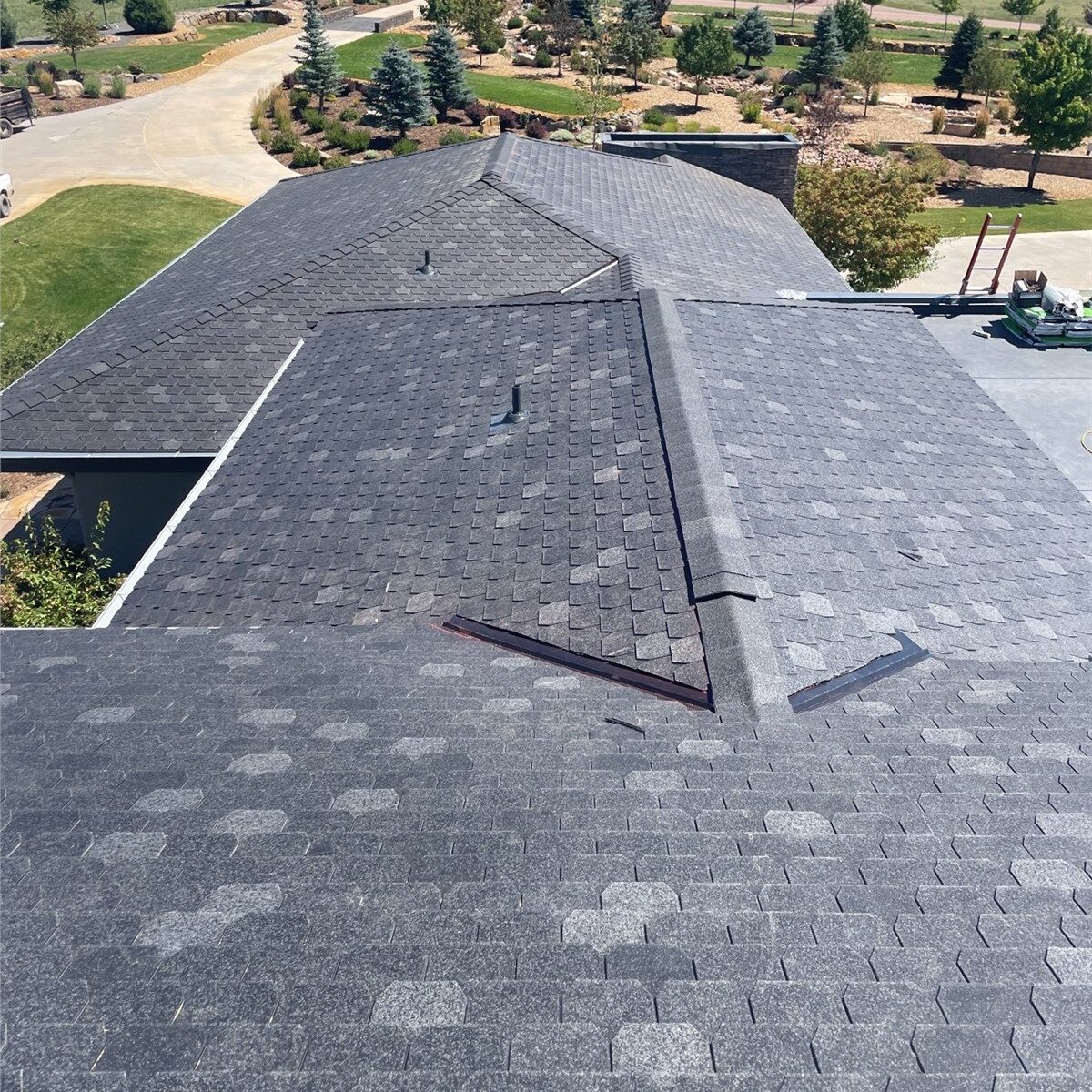 High-angle view of a residential roof featuring unique dark gray hexagonal asphalt shingles overlooking a scenic landscape.
